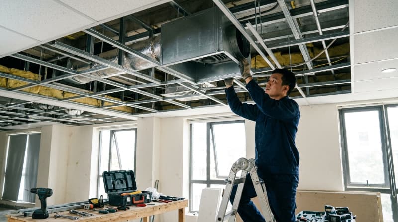 Kỹ thuật viên kiểm tra phần hộp quạt và đấu nối hệ thống điện âm trần trước khi cố định mặt nạ bảo vệ cho thiết bị.