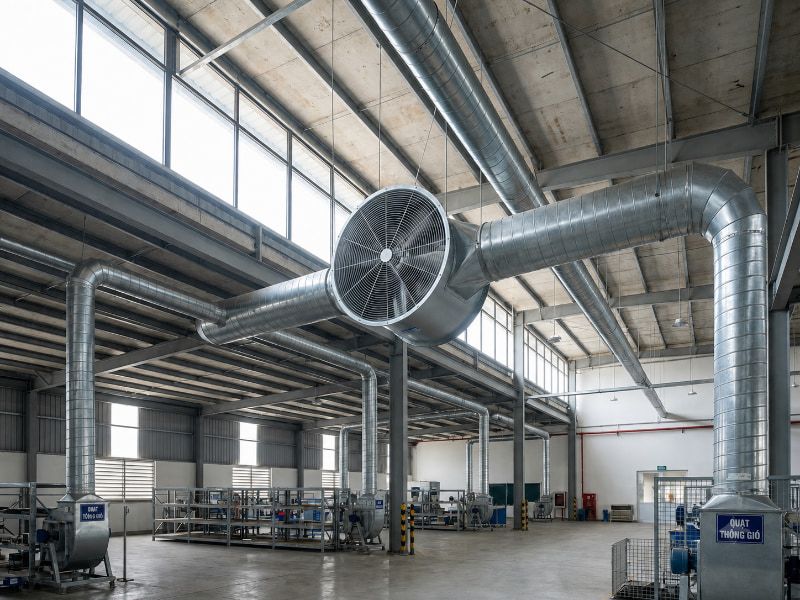 Cách chọn đúng cấu tạo, loại quạt thông gió tròn 2026 4 Thực tế lắp đặt quạt thông gió tròn công nghiệp trên đường ống trần nhà xưởng.